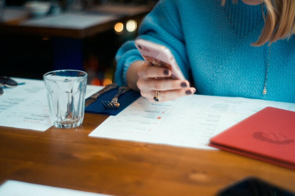 A woman checking work emails when out for dinner